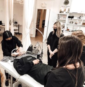 ladies doing facial treatment on a woman's face